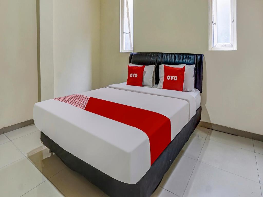 玛琅OYO 91084 Oke Guest House的卧室内的一张带红色枕头的大床