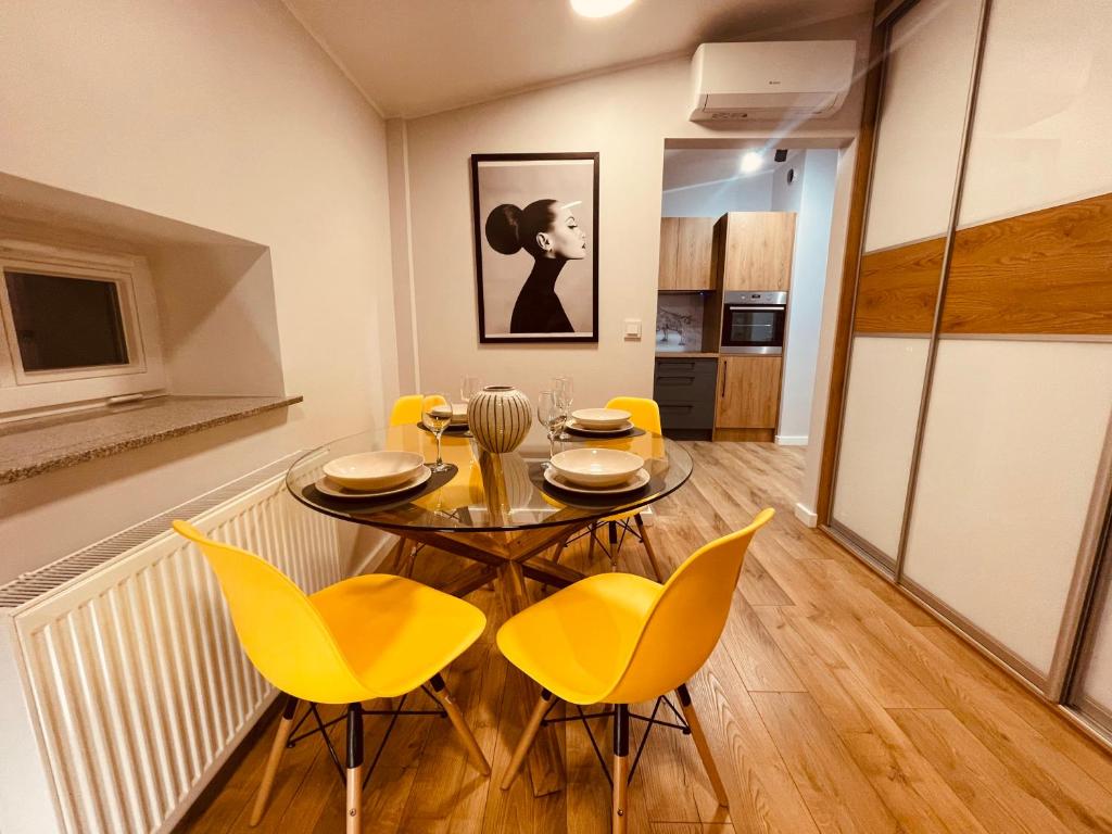 卡托维兹Apartamenty KTW Kościuszki 41 - SKY & DESIGN的一间带桌子和黄色椅子的用餐室
