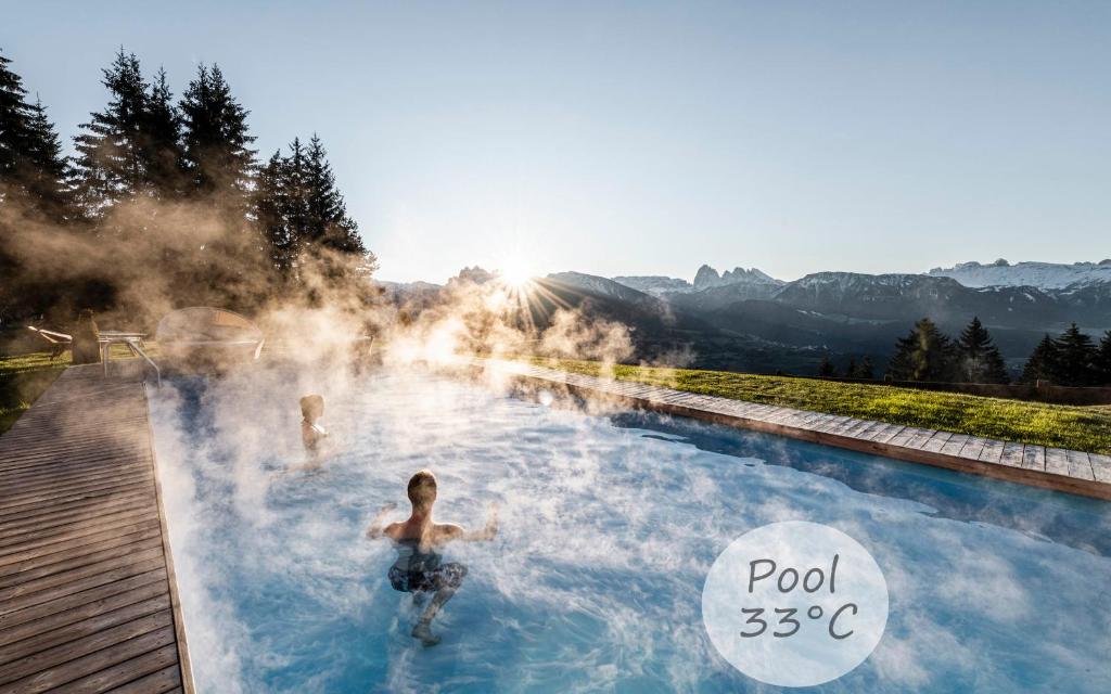 维兰德罗Granpanorama Wellnesshotel Sambergerhof Superior的两人在带蒸汽的温泉池游泳