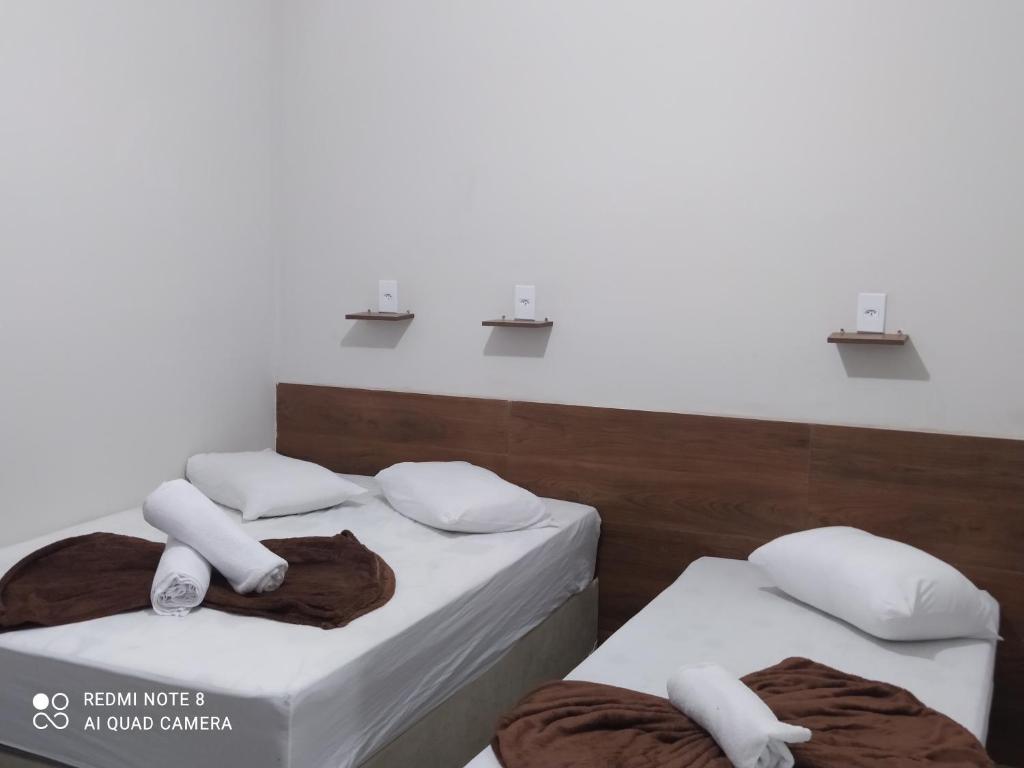 阿帕雷西达Pousada Quarto com ventilador,ar frigobar e garagem的白色墙壁客房中的两张单人床