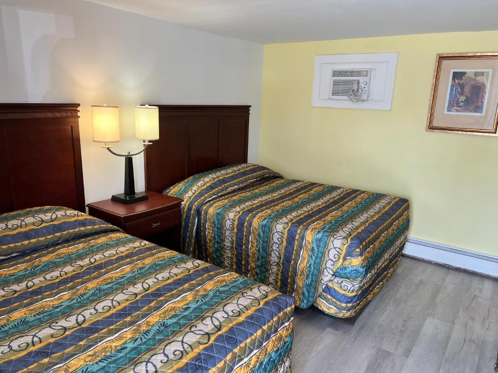 萨默斯波因特萨默斯浦银特超值汽车旅馆套房酒店的酒店客房设有两张床和一张桌子上的台灯。