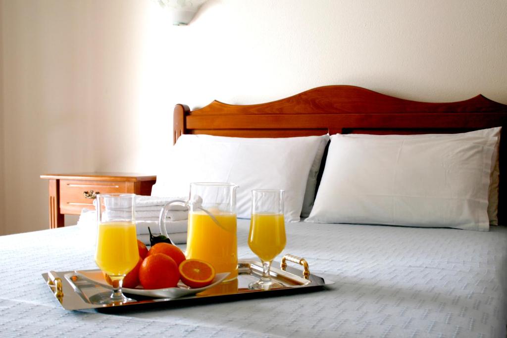 米利纳Zouzoulas Filoxenia - Koralia Apartments的床上的托盘,上面放有两杯橙汁和水果