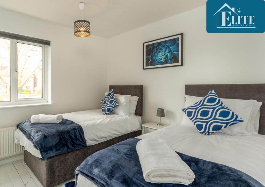 利明顿温泉House with Garden & Private Driveway - Elite Properties的一间卧室配有两张带蓝白色枕头的床