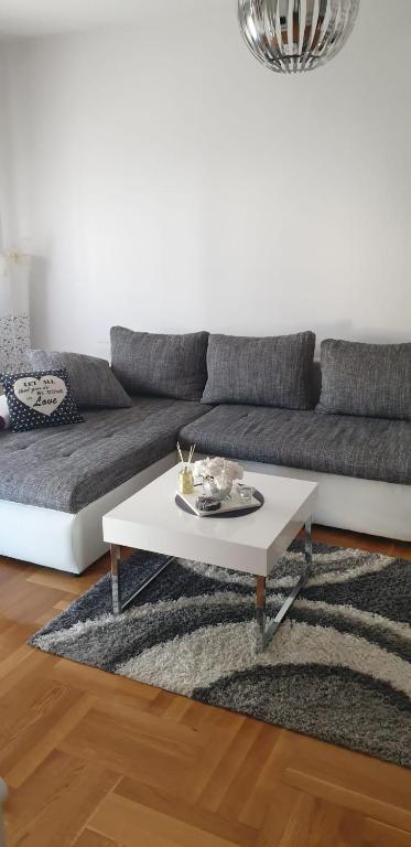 萨格勒布Apartman Aura的带沙发和白色咖啡桌的客厅