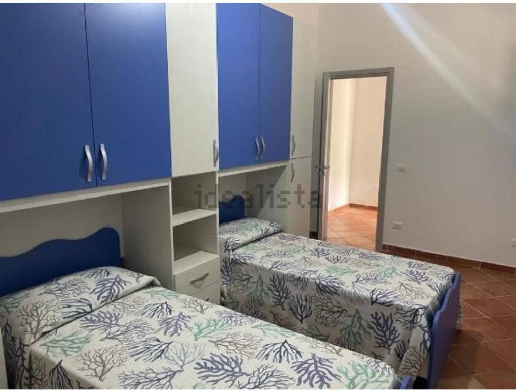 约波洛Villa Caterina的配有蓝色橱柜的客房内的两张床