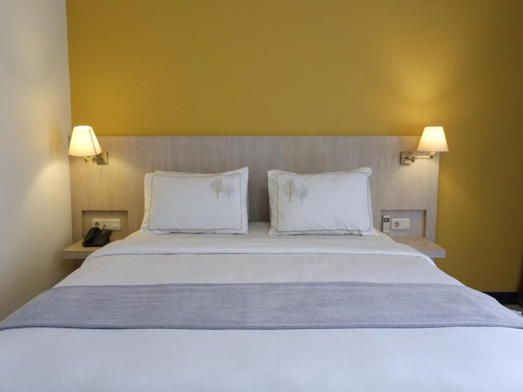 巨港Rio City Hotel的卧室配有一张带两个枕头的大白色床