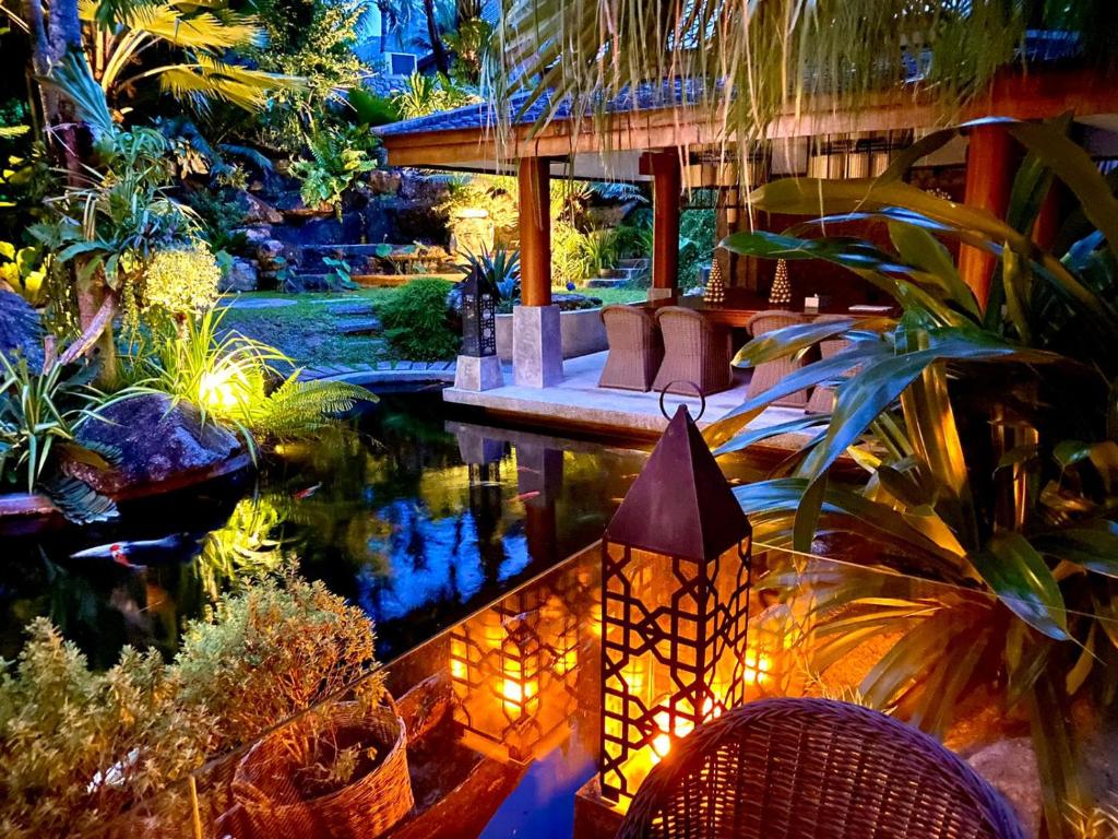 苏林海滩Villa on The Rocks, 4 bedrooms, Phuket的花园中带池塘的房子