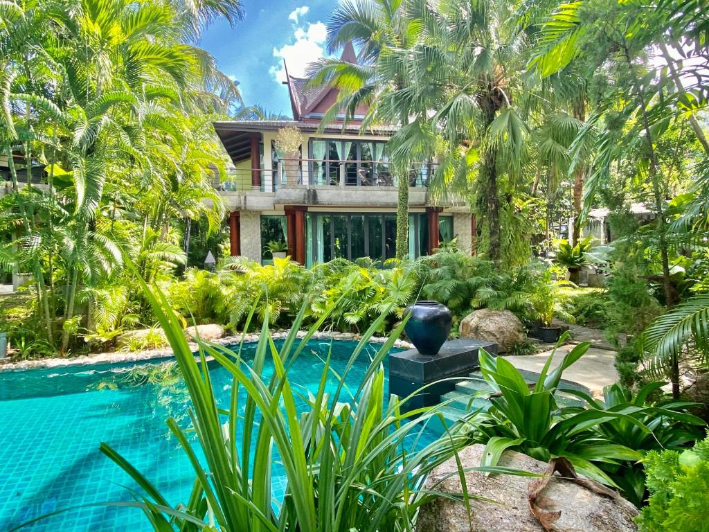 苏林海滩Villa in the Garden, Surin Beach with private spa.的一座带游泳池和棕榈树的房子