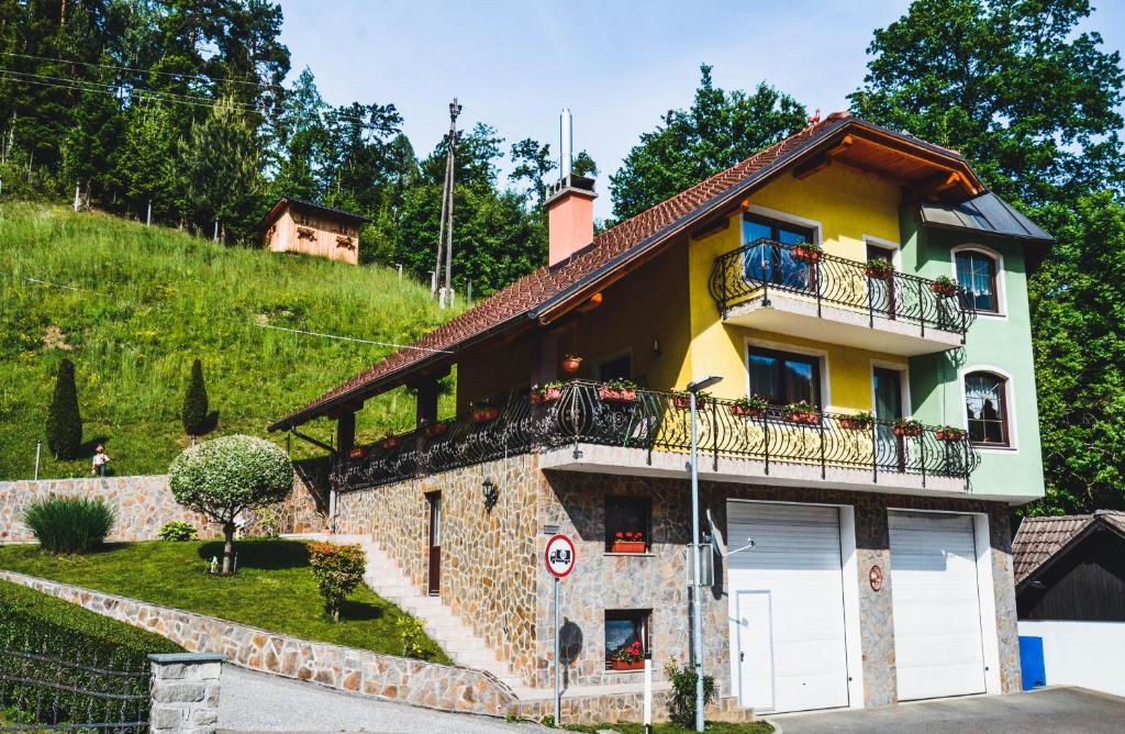 MežicaApartmaji Krebs的山丘上带阳台的黄色房子