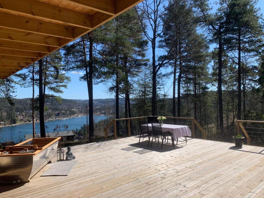 BrevikSummer cabin in Nesodden open-air bath large terrace的湖景木制甲板,配有桌子