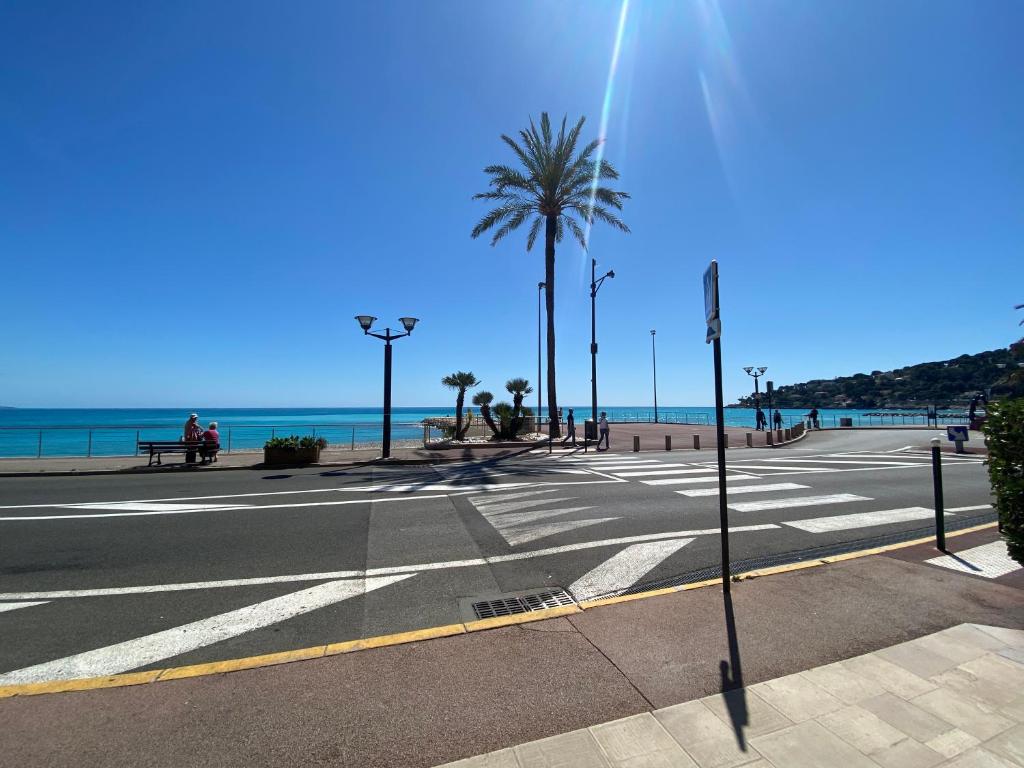 罗克布吕讷-卡普马丹Cosy 2 pièces, résidence en front de mer, Roquebrune Cap Martin的一条空的街道,有棕榈树和海滩