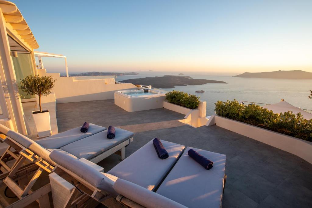 菲罗斯特法尼Sunset View Villa Santorini - with Outdoor Jacuzzi的配有蓝色桌子和浴缸的庭院