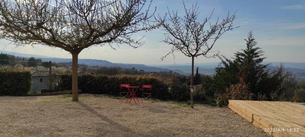 博尼约Une escapade en Luberon的树下两把红色椅子和一张桌子