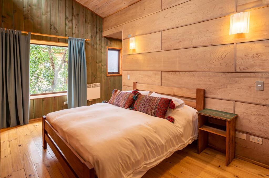 普孔Espacio Ecole Pucon的一间卧室设有木墙和一张带窗户的床