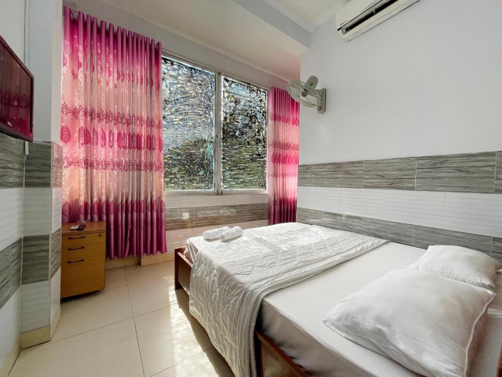 胡志明市Huy Hoàng Hotel的一间卧室配有床和一个带粉红色窗帘的窗户。