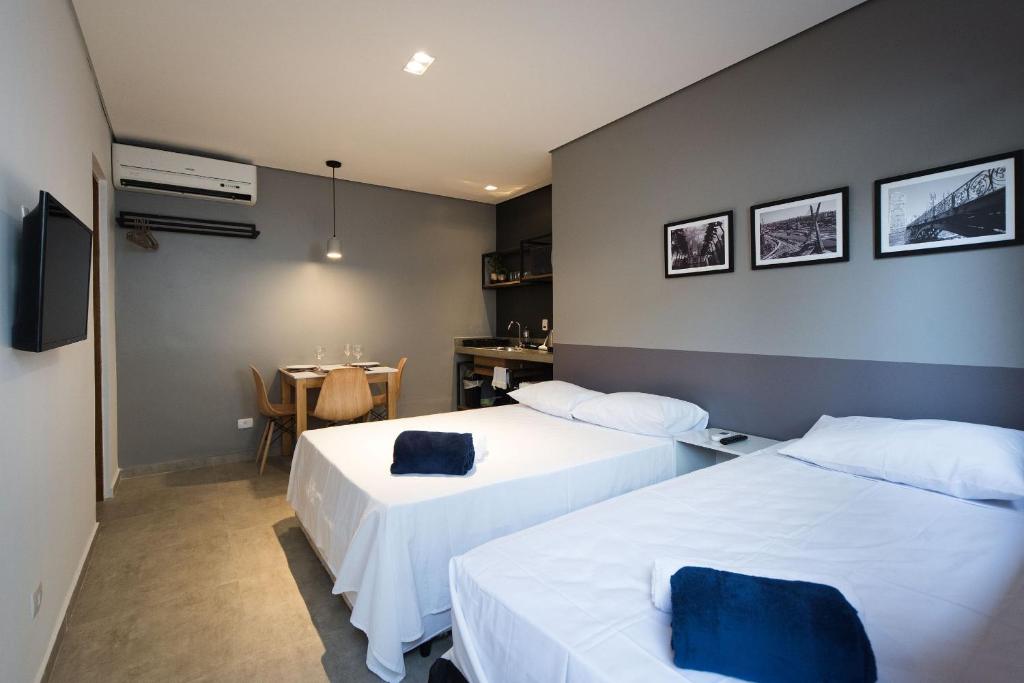 圣保罗Studio 2 Pinheiros by Oba的酒店客房设有两张床和一张桌子。
