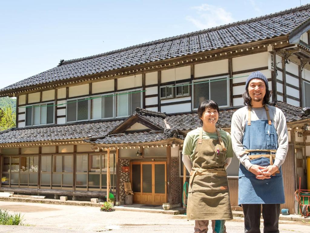南砺Guest House Takazuri-KITA的两名妇女站在一座建筑物前面