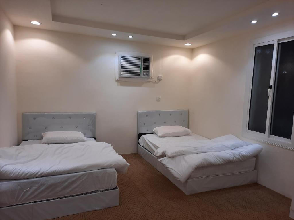 Madain Salehمزرعة ارياف العلا的配有2张床的白色墙壁和窗户。
