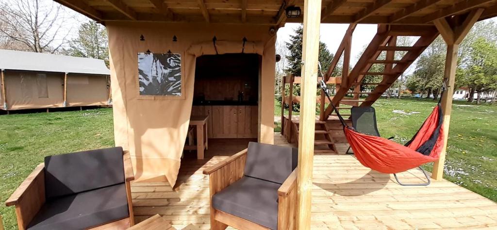 巴涅斯Tente Cabane du Camping Hautoreille的门廊配有2把椅子和吊床
