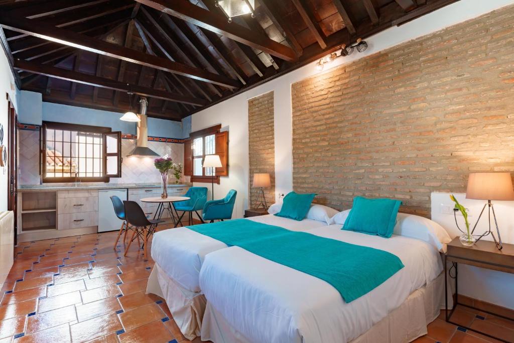 格拉纳达SUITES CASA DE LAS COLUMNAS的一间卧室设有一张大床和砖墙