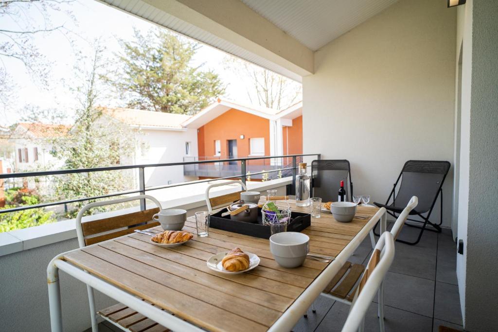 拉特斯特德布赫SEAHORSE - Spacieux Appartement proche du port de la Teste的阳台配有带食物的木桌。