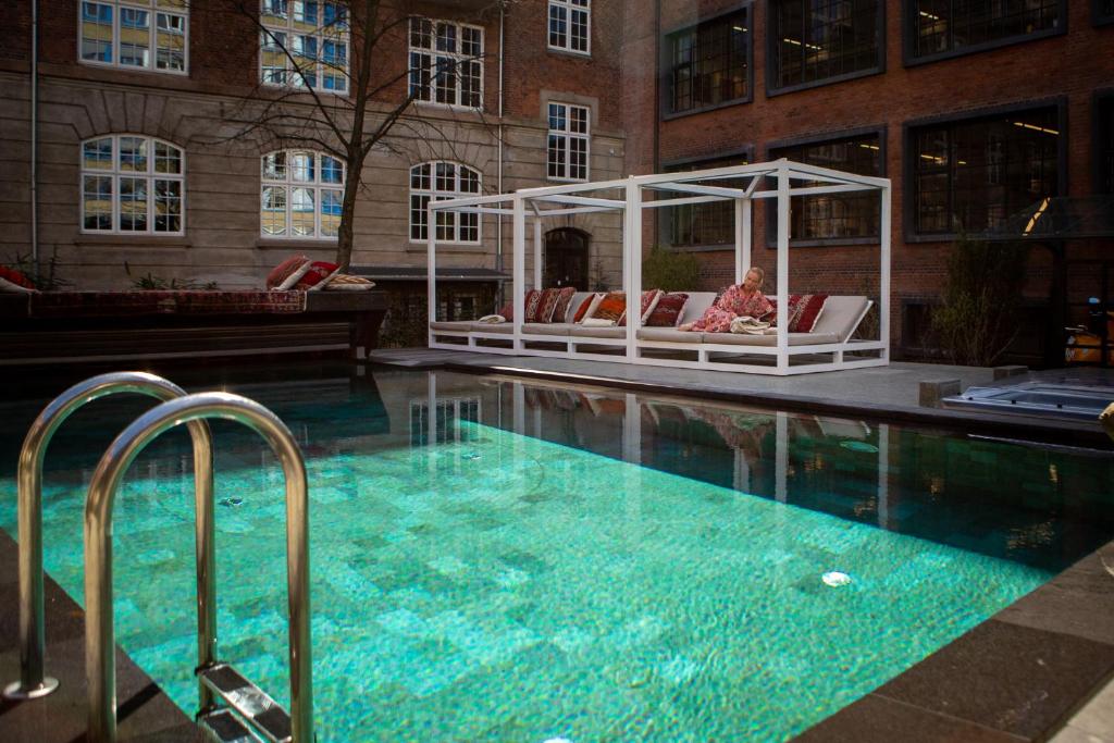 哥本哈根Bryggen Guldsmeden的一座带椅子的游泳池和一座毗邻大楼的凉亭