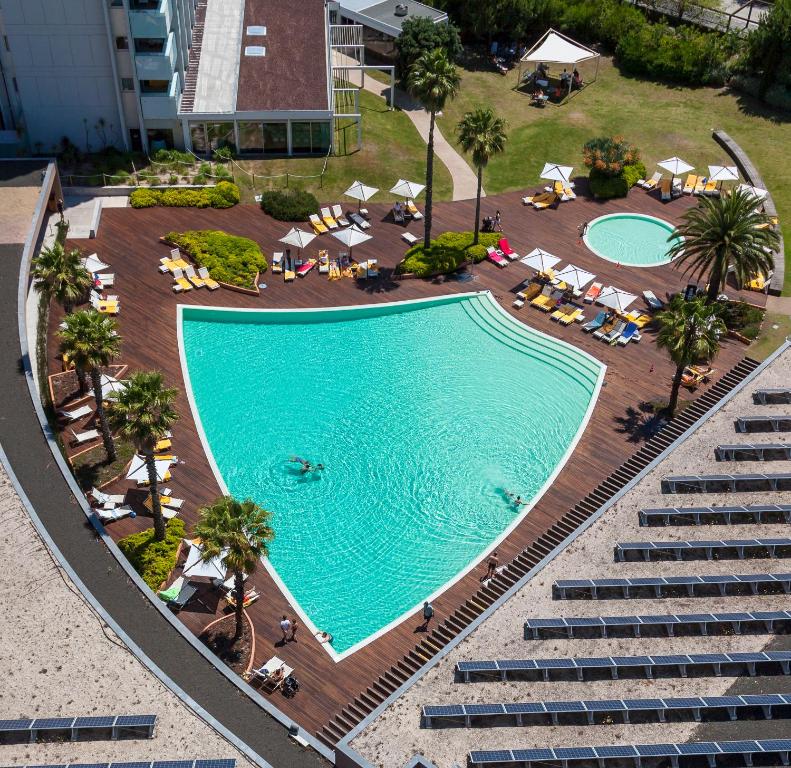 特罗亚Aqualuz Troia Rio by The Editory的享有带椅子和棕榈树的游泳池的顶部景致