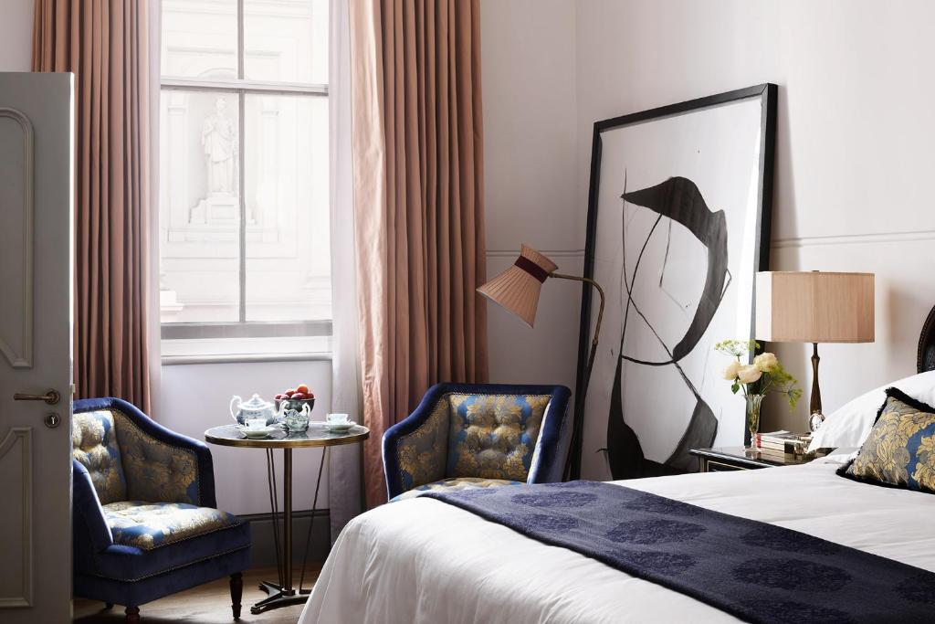 伦敦NoMad London的酒店客房,配有一张床和两把椅子