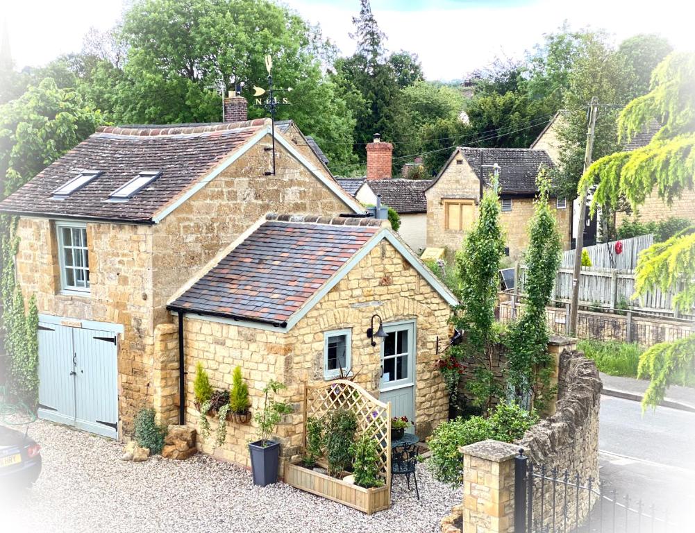 MickletonThe Loft in the Malt Barn Chipping Campden的一座古老的石头房子,设有蓝色车库