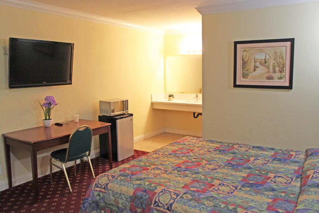 波莫纳罗伊拉汽车旅馆的一间酒店客房,设有一张床铺、一张桌子和一张床,
