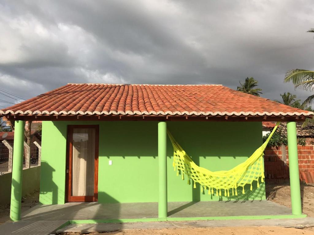 BarroquinhaMar Aberto_chale 3的绿色建筑,设有红色屋顶和黄色吊床