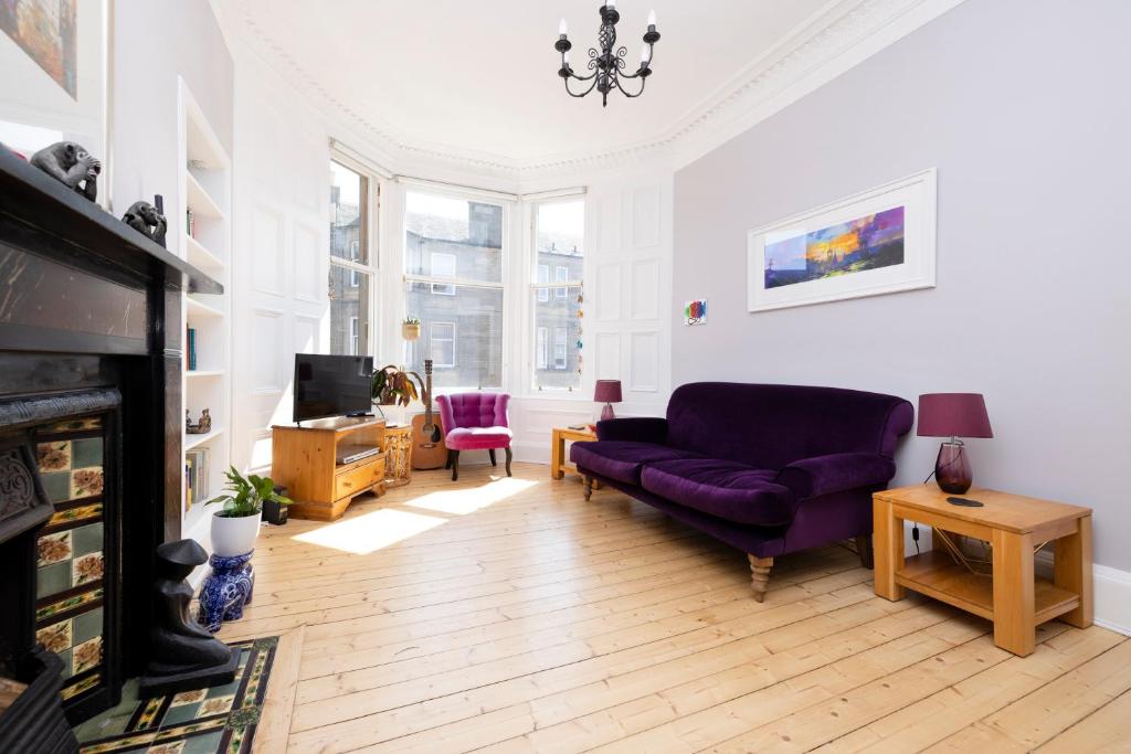 爱丁堡JOIVY Gorgeous 1-bed flat with a shared garden的客厅配有紫色沙发和电视