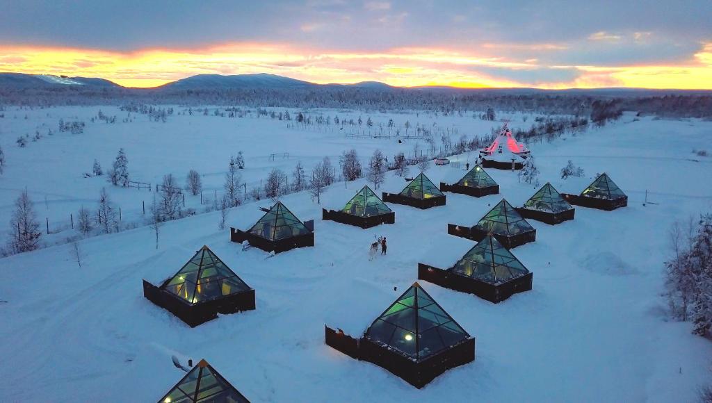 KöngäsAurora Pyramid Glass Igloos的日落时分积雪中的一组小屋