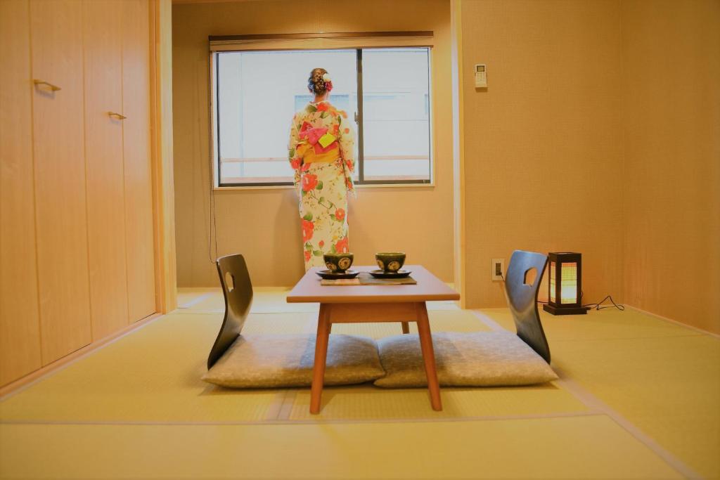 京都Kamozen Kyoto Machiya Stay的站在房间里和服的女人