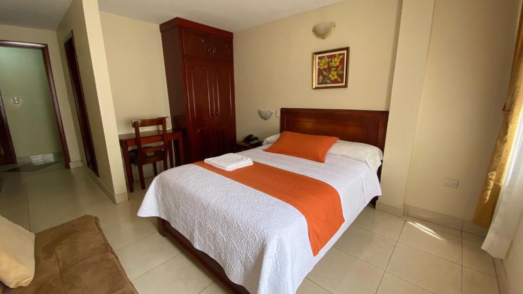 洛哈Hotel Caluva的一间卧室配有一张带橙色和白色毯子的床