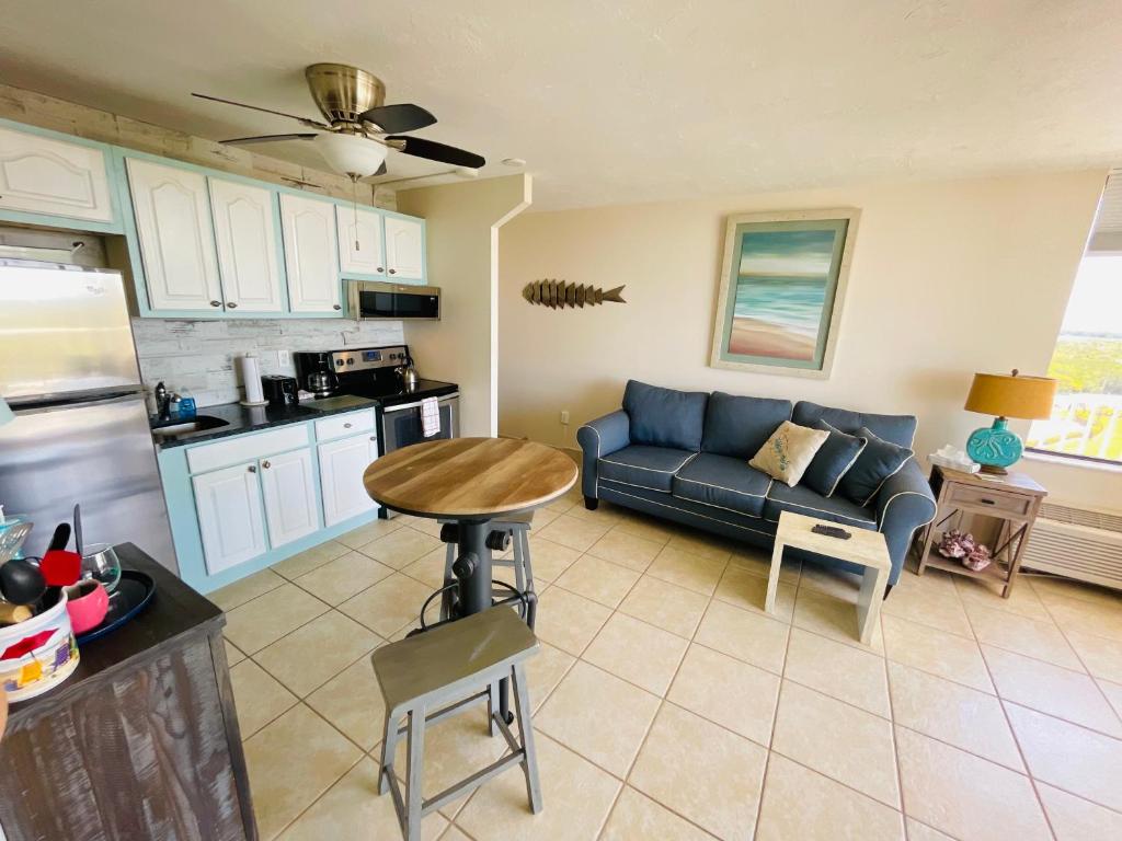 迈尔斯堡海滩#808 Lovers Key Beach Club的一间带蓝色沙发的客厅和一间厨房