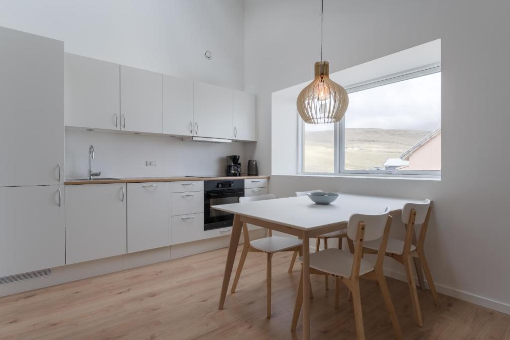 MiðvágurBrand New / Airport / RentYourCar / Free Parking的厨房配有白色橱柜和桌椅