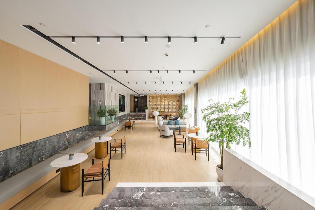重庆重庆西站亚朵酒店的一个带桌椅的大堂和一间客厅