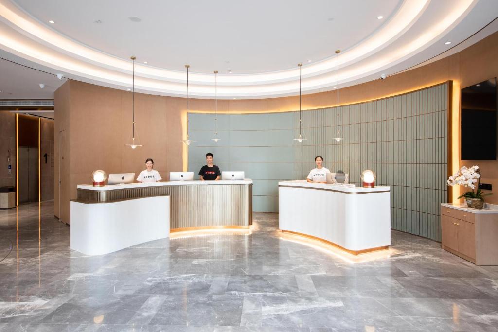 武汉武汉国际博览中心四新亚朵酒店的酒店大堂,有三人坐在书桌上