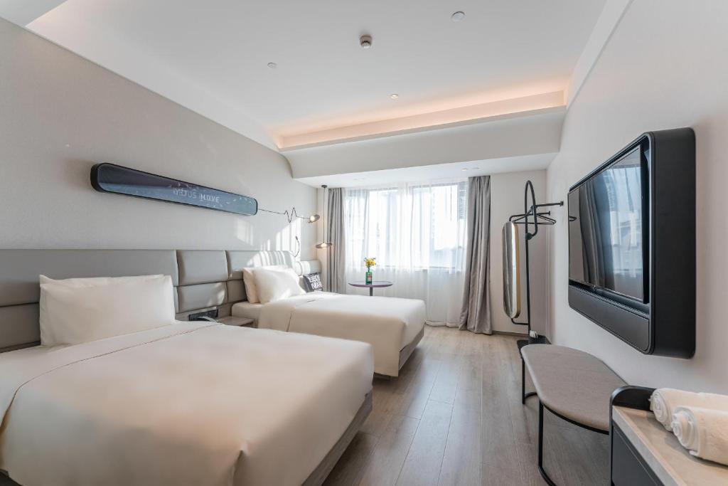 苏州苏州盘门古运河轻居音乐酒店的酒店客房设有两张床和一台平面电视。