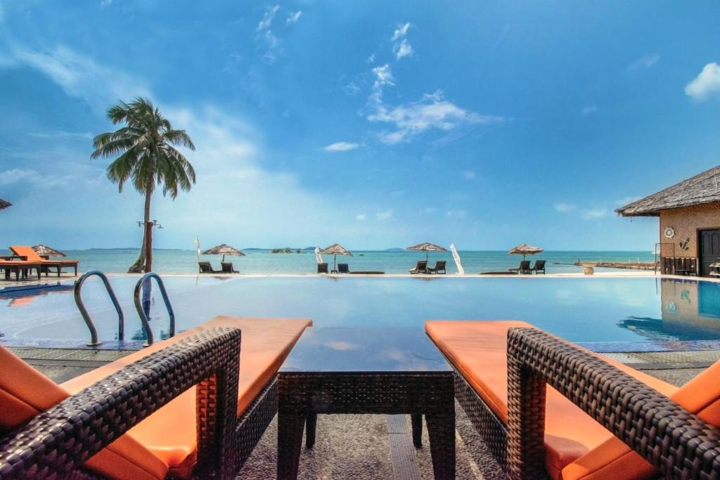特鲁克巴库民丹岛别墅海滩温泉度假酒店的一个带椅子的游泳池,背景是大海