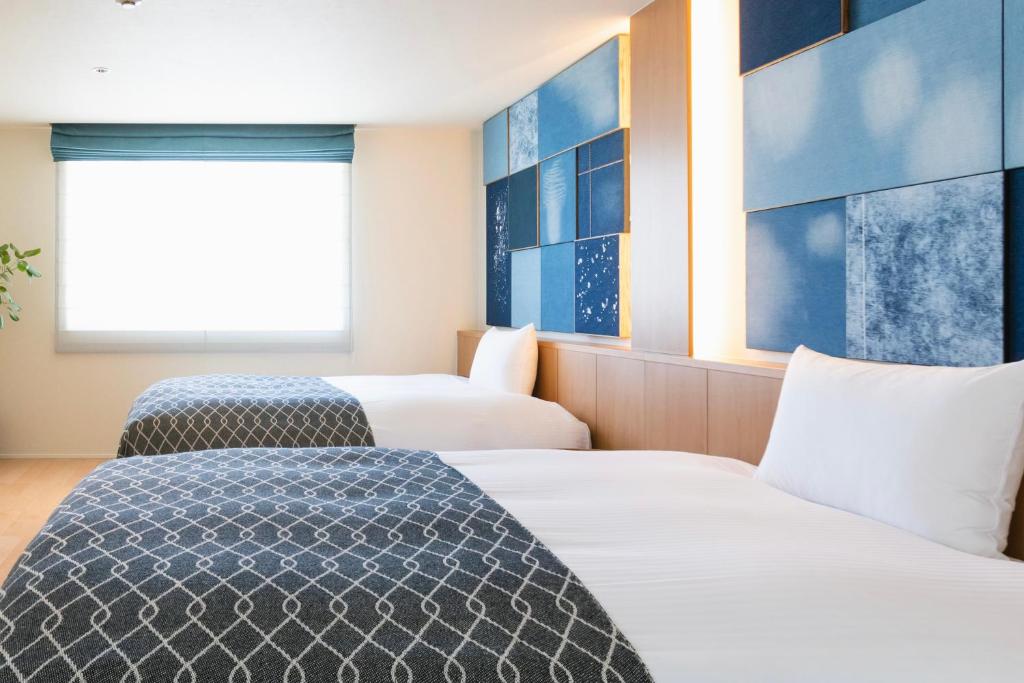 仓敷Nagi Kurashiki Hotel&Lounge的酒店客房设有两张床和窗户。