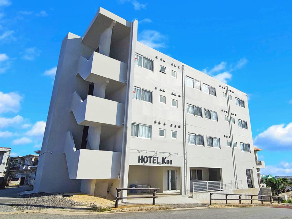 宫古岛HOTEL Kuu的一座白色的大建筑,前面有两长椅