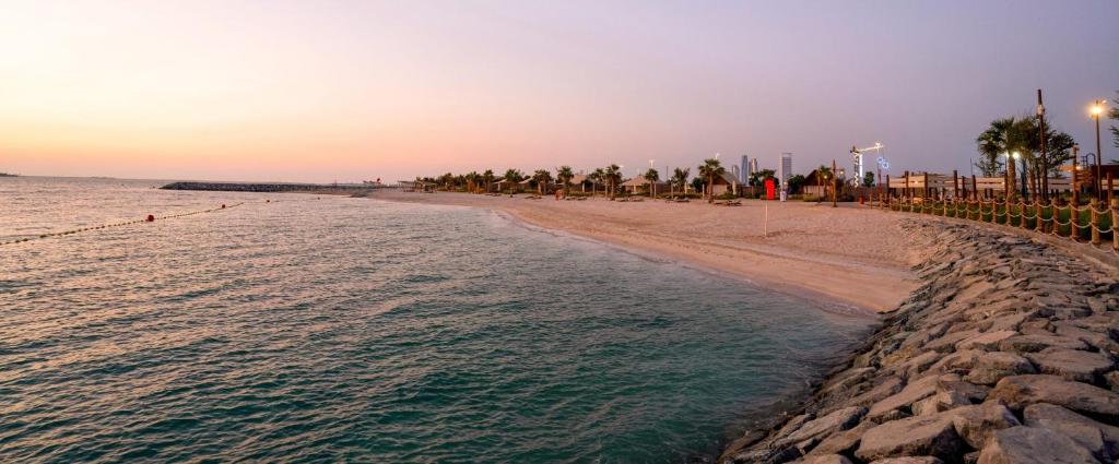 阿布扎比Bab Al Nojoum Hudayriyat Camp的日落时分拥有棕榈树和海洋的海滩