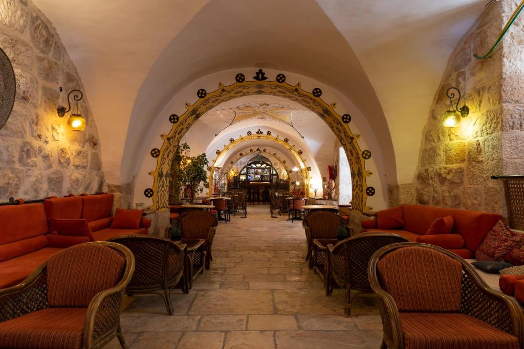 耶路撒冷Gloria Hotel的大楼内一家带橙色椅子和桌子的餐厅
