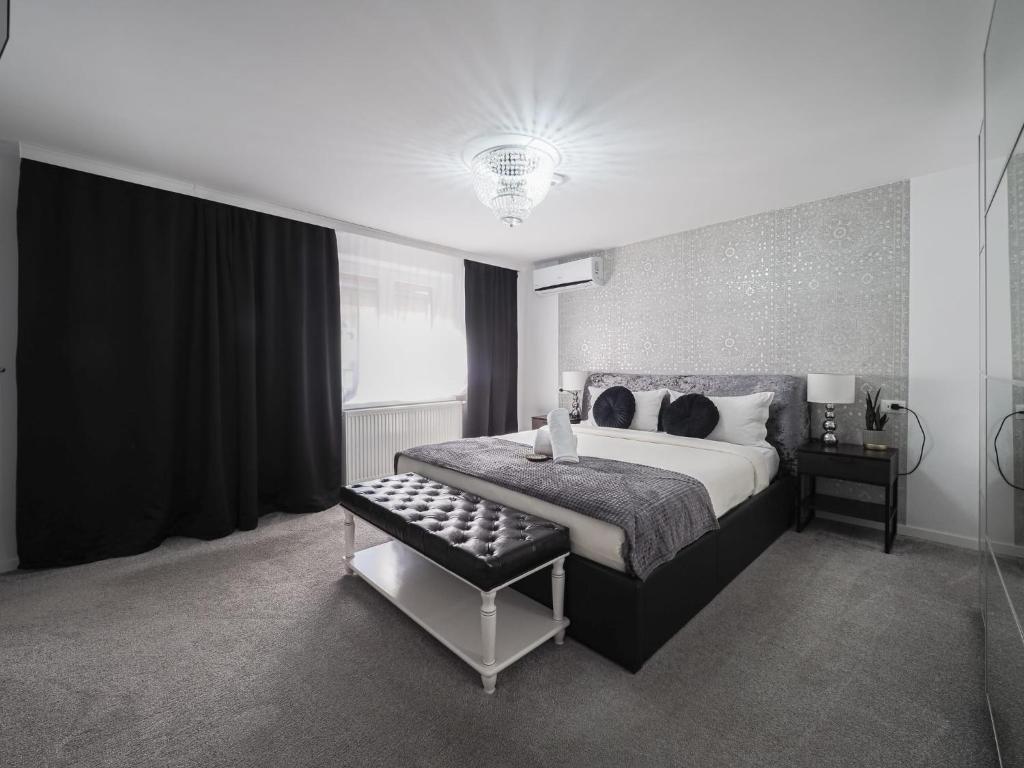 锡比乌For You Apartments Gold & Silver的黑白卧室,配有床和凳子