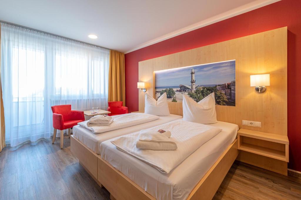 罗斯托克Das Hotel an der Stadthalle - Rostock Hauptbahnhof的酒店客房设有一张大床和红色的墙壁。