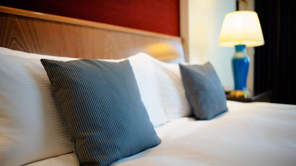 华沙华沙洲际酒店的一张带蓝色和白色枕头的床和一盏灯