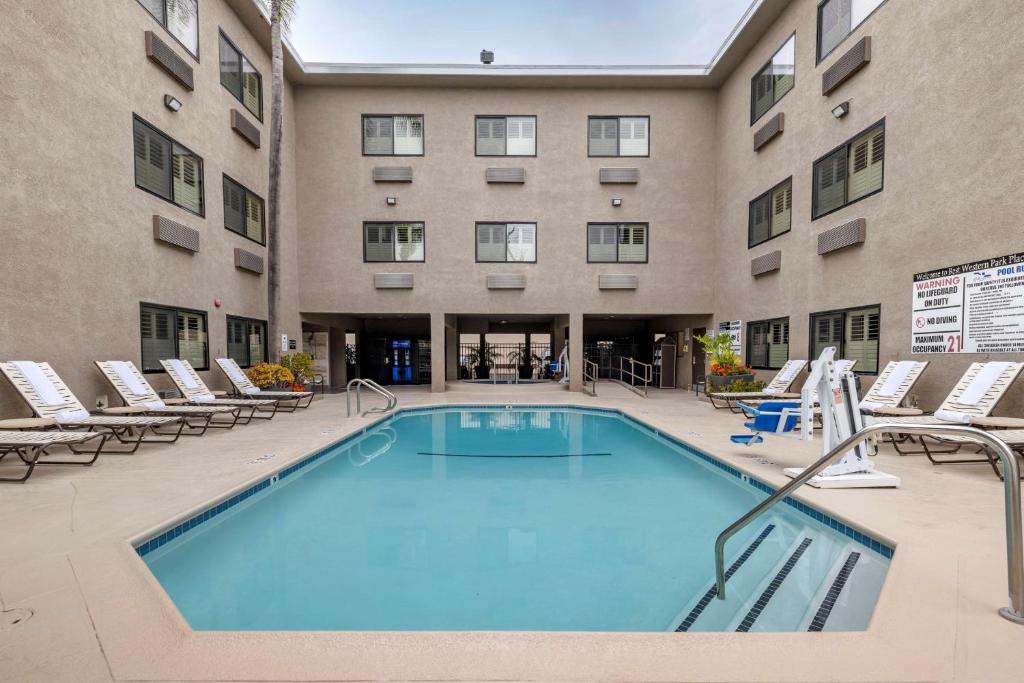 安纳海姆Best Western Plus Park Place Inn - Mini Suites的一座带躺椅的建筑前的游泳池