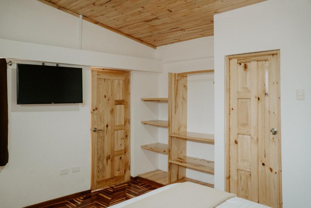 瓦拉斯Atusparia Guest House Huaraz的一间设有床铺和墙上电视的房间